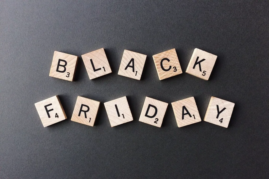 Blocos de madeira com letras formando a frase "Black Friday" sobre uma superfície cinza escura.