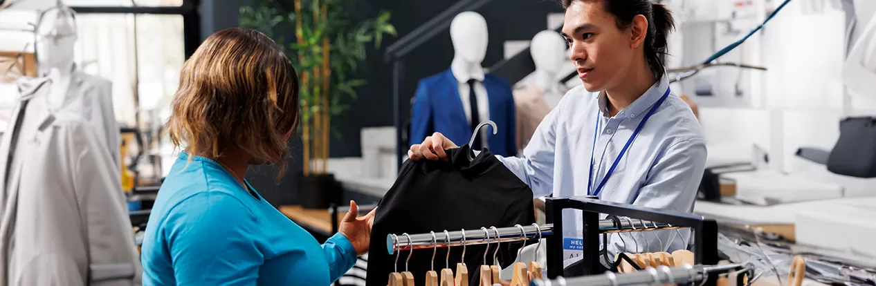 Homem atendendo uma cliente em loja de roupas