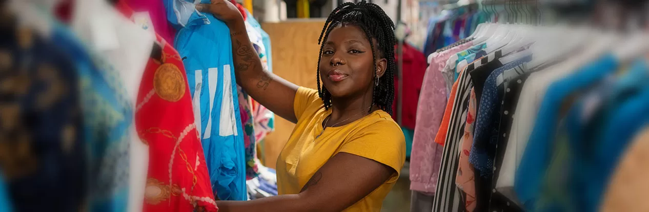 Mulher repondo roupas na arara em uma loja de roupas